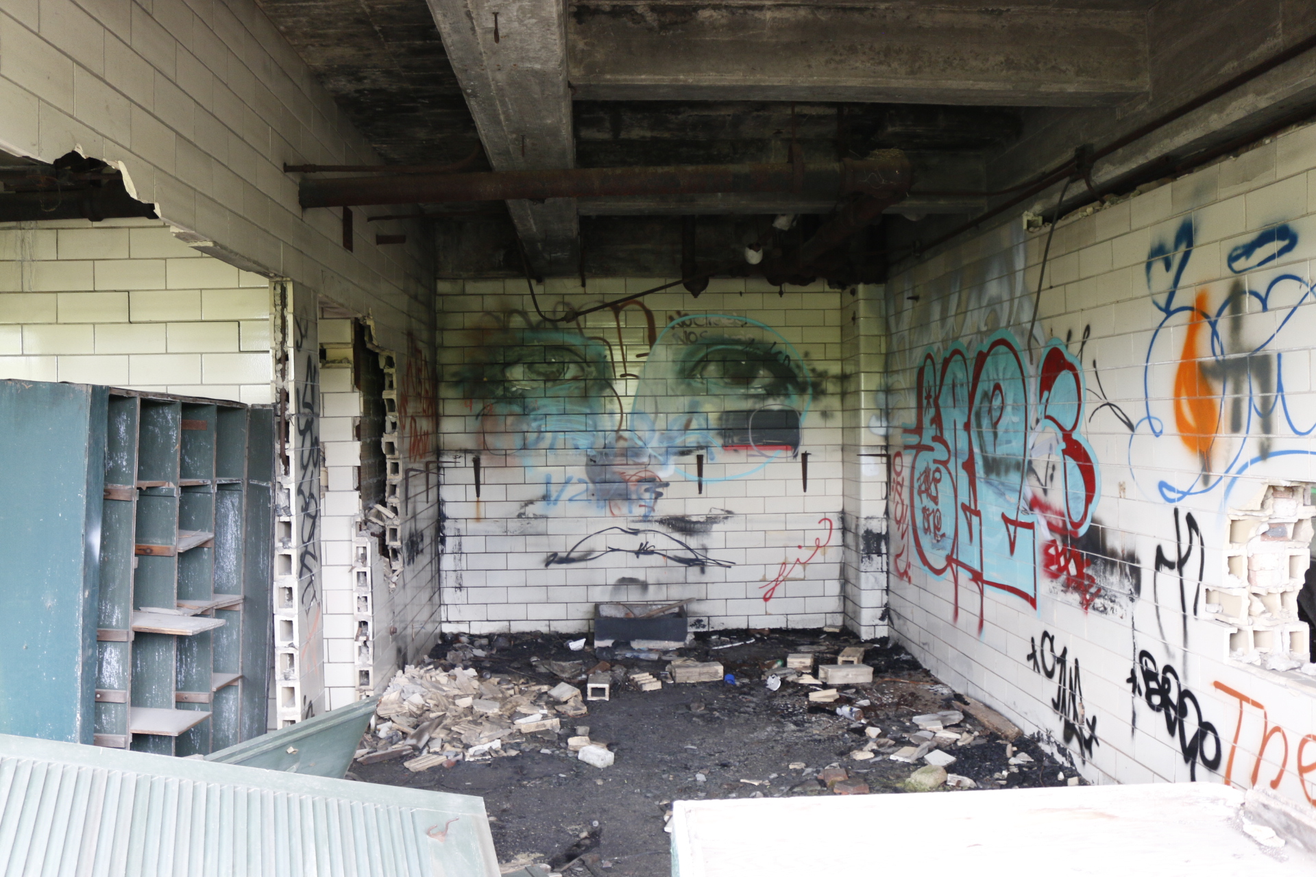 A derelict tiled room thick with graffiti, a painted pair of eyes on the far wall above scattered debris